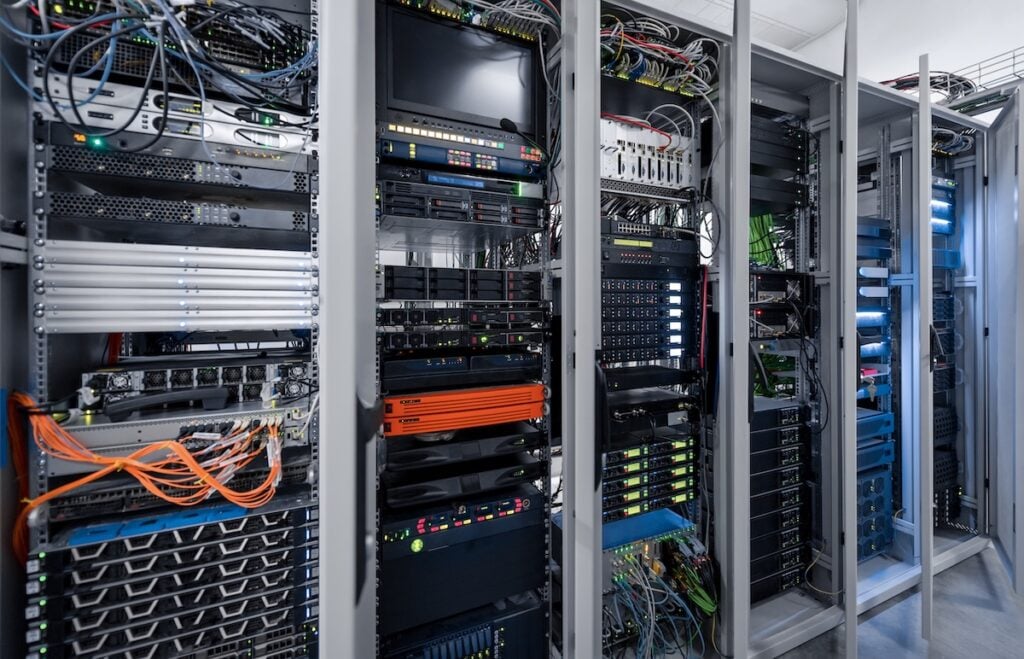 Six server racks with opened doors. Server room with numerous computers and routers. Data center.