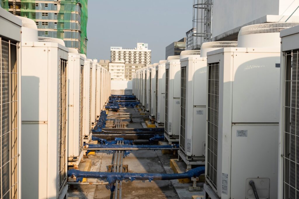 Rows of rooftop HVACs on the roof deck of an office tower.