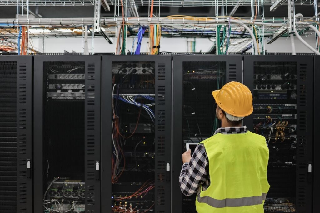 technician man working with tablet inside big data center room