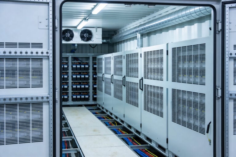 crac unit A view inside a climate-controlled containerized data center featuring rows of server cabinets and a battery backup system with visible cabling