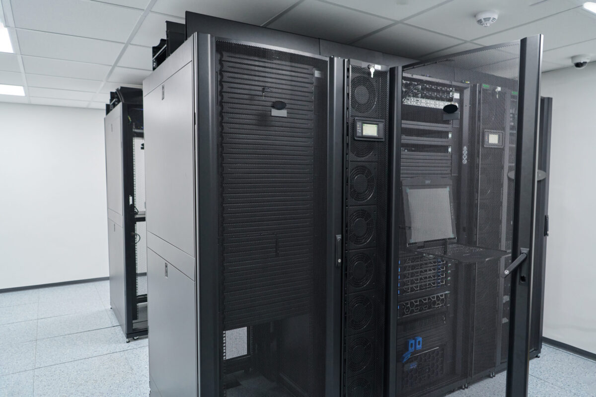 data center cooling solutions Secure, modern data center interior showing black server racks, network switches and cooling units in a clean, climate-controlled server room for enterprise IT infrastructure and cloud services.