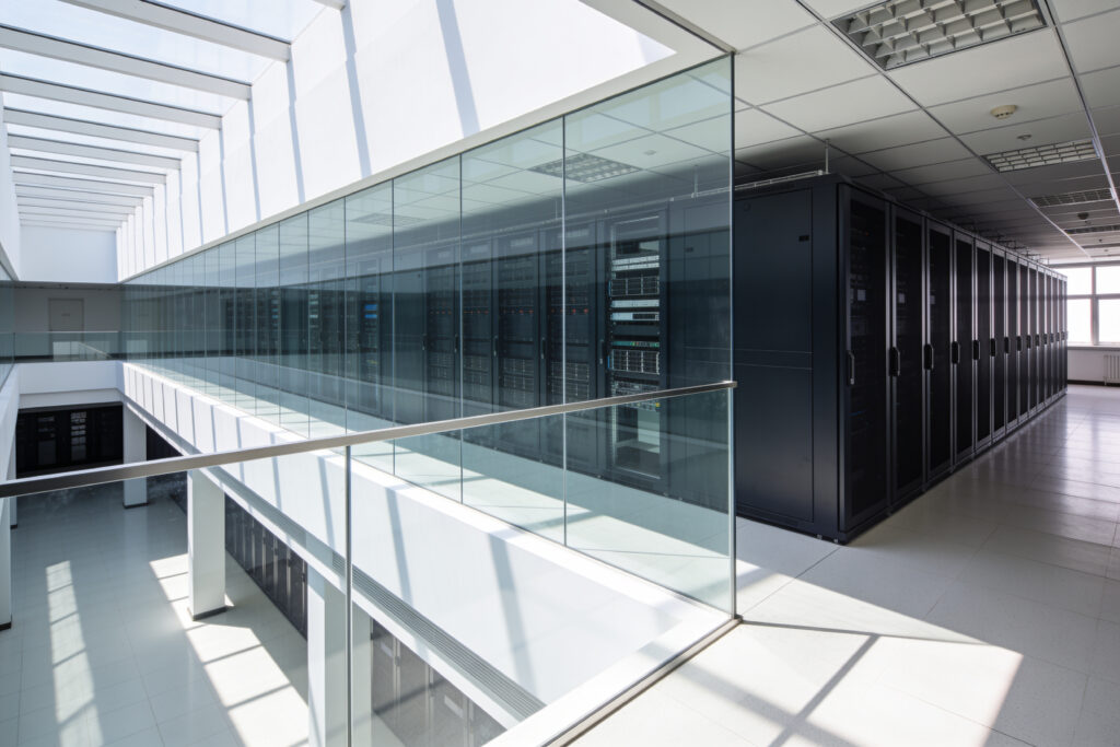 server racks A bright, contemporary data center interior featuring rows of black server cabinets visible through a sleek glass partition and walkway